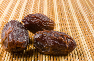 Big luxury dried date fruit on the bamboo mat, kurma ramadan kareem concept, close up.