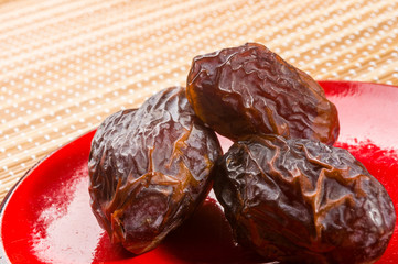 Big luxury dried date fruit in bowls on the bamboo mat, kurma ramadan kareem concept, close up.