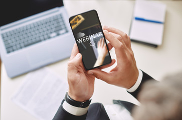 Webinar concept, online training. man holding a smartphone in his hands with the inscription Webinar