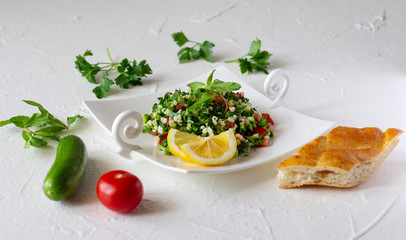 Tabbouleh salad, bread and fresh ingredient vegetables.  Vegetarian salad with bulgur wheat, chopped tomato, cucumber, parsley and mint. Lebanese and Middle Eastern cuisine