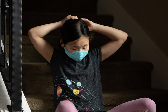 Asian girl adjusts ties on cloth mask behind head