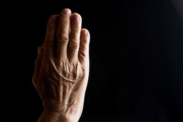 Praying old grandmother in silence close-up. Old wrinkled hands in prayer. Wrinkles on old mother hands closeup. Aged mother asks God for the protection of children. Parents value social photo. 