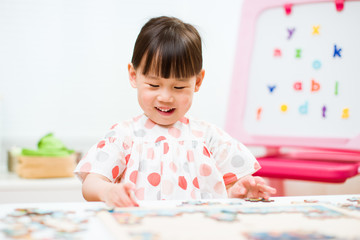 toddler girl playing wooden puzzle at home