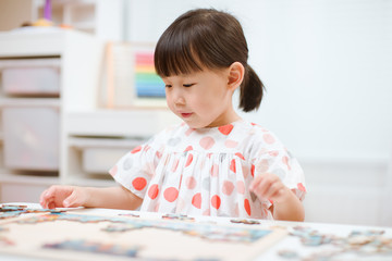 toddler girl playing wooden puzzle at home