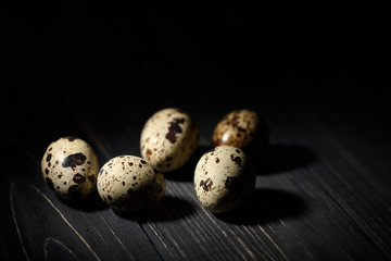Quail eggs close-up on a black wooden table in hard light