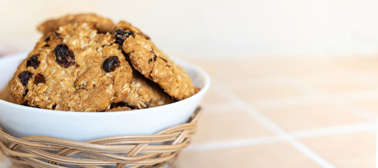 Oatmeal cookies with raisins in a white bowl.