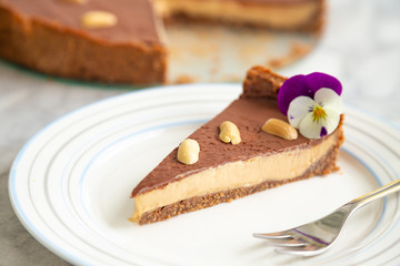 Slice of raw homemade vegan peanut butter mousse cake with walnuts and dates crust