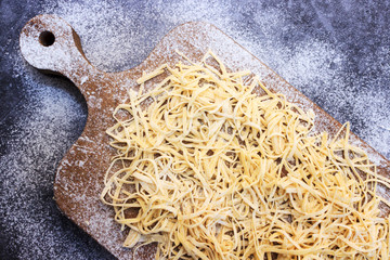 Men hands roll out dough close up. Man preparing dough for cooking pasta on a wooden table