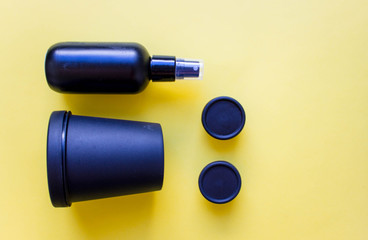 black plastic containers made from recycled plastic and reused for cosmetics on yellow background. Concept of recycling and eco-friendly use. Free copy space. Top view