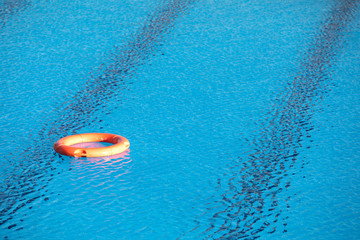 Orange lifebuoy floating on a pool