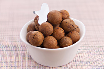 delicious macadamia nuts on  plate on  wooden background