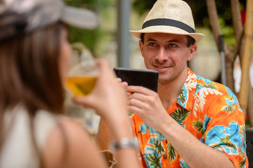 Happy multi ethnic tourist couple taking picture with phone at restaurant