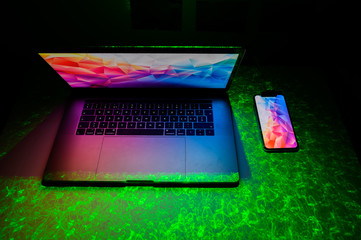 Open laptop with digital tablet and white smartphone. All with isolated screen on modern LED desk....