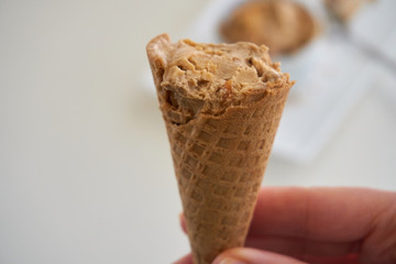 Hand holding a bitten Ice Cream cone - white background  gluten-free waffle cone 