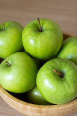 Green apples in a wooden bowl close - up view from above