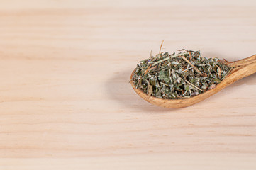 dry black tea with mountain herbs scattered on a light background with a wooden spoon. healthy eating concept copy spase.