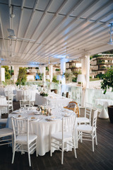 Wedding dinner table reception. Round banquet table with white tablecloth and white Chiavari chairs. Wedding under the tent. 