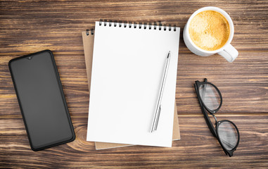 Notebook with pen, smartphone, glasses and coffee.
