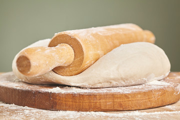 Raw wheat dough on wooden cutting board. Close up
