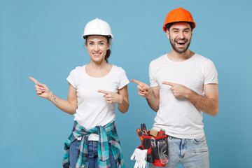 Smiling couple woman man in casual clothes protective helmet hardhat isolated on blue background....
