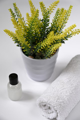 The bottle of natural herbal shower gel for women with towel on the table with flowers in bathroom.