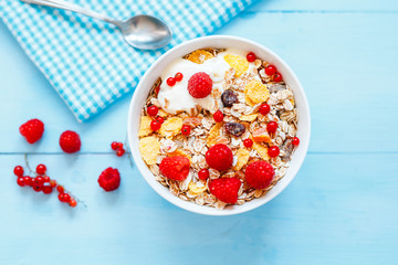 Delicious breakfast. With oat flakes, dried fruit and yogurt on a blue background.