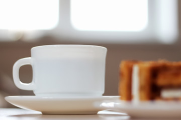 Close-up of a white coffee Cup with dessert for Breakfast on the office table. Concept of cooking and dining during working hours