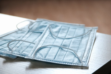 Two protective blue medical face masks on the edge of the table. The concept of safety and prevention during an epidemic of viral infection COVID-19