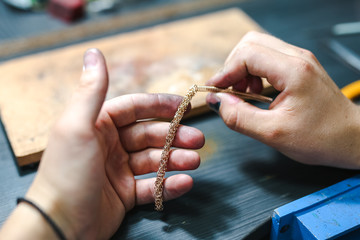 Master goldsmith while working on jewelry on the of work table.