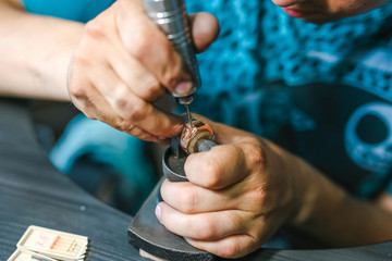 Master of jewelry while working on gold ring.