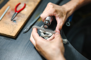 Master goldsmith while working on jewelry on the of work table.