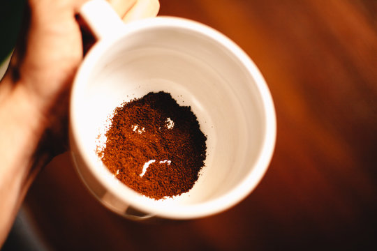 Dissatisfied anthropomorphic face formed of coffee ground in mug. Bad morning