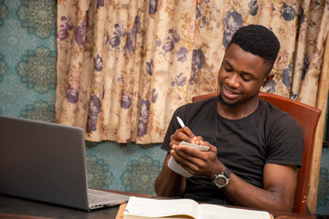 young african student receiving lectures online, taking notes