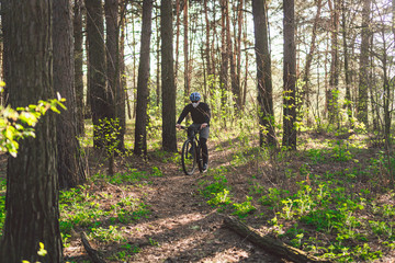 Naklejka premium Young man in protective mask from environmental pollution riding mountain bike on cross country road. Cyclist Riding the Bike on Trail in Forest. Face pollution mask smog dust pm2.5 protection