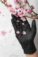 Hand in a black glove holds a flowering branch
