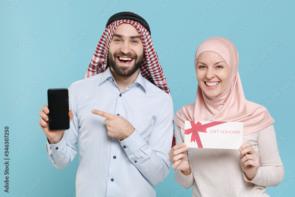 Wall mural couple friends arabian muslim man wonam in keffiyeh kafiya ring agal hijab clothes isolated on blue 