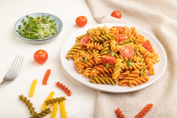 Tortiglioni semolina pasta with tomato and microgreen sprouts on a white wooden background. Side view, close up.