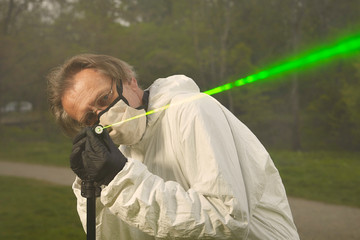 Criminologist technician in protective suit and mask working with ballistics laser