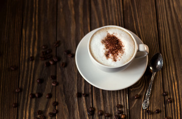 a Cup of coffee with milk and coffee beans on a dark wooden background. selective focus