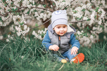 A boy walks in the garden with flowering trees.
