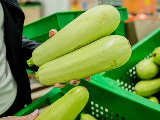 Woman chooses squash or zucchini in grocery store