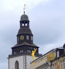 Turm der Stadtkirche von Gießen mit goldener Skulptur auf einem Dach im Vordergrund