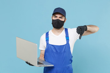 Delivery man in cap t-shirt uniform sterile mask gloves isolated on blue background studio. Guy employee courier hold laptop pc computer Service quarantine coronavirus virus covid-19 2019-ncov concept