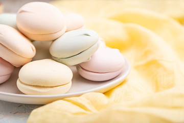 Colored zephyr or marshmallow  on yellow textile. Side view, selective focus.