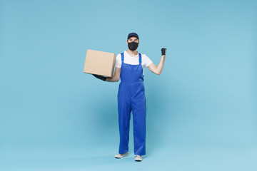 Full length delivery man in cap t-shirt uniform sterile face mask gloves isolated on blue background studio Guy employee courier hold box Service pandemic coronavirus virus covid-19 2019-ncov concept.