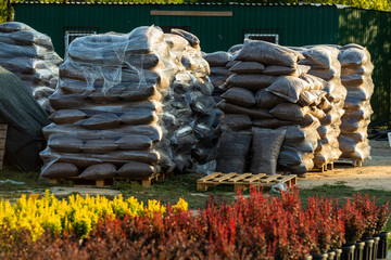 plastic bags with oak bark and wood chips for decorating paths and flower beds folded on pallets...