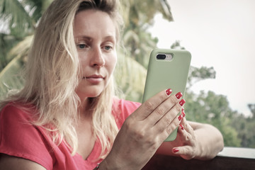 Adult blond woman holding , using and looking at smart phone