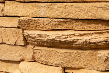 A fragment of wall decoration made of artificial yellow finishing stone for wall decoration. Close up.