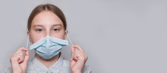 teenager girl 12-15 years old, removes medical mask, end of virus, disease gone, recovery and freedom, child recovered, free space for copy text. Flu infection disease and pandemic. Gray background.