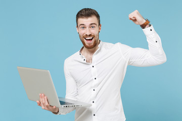 Excited young bearded man guy 20s in white classic shirt isolated on pastel blue wall background....